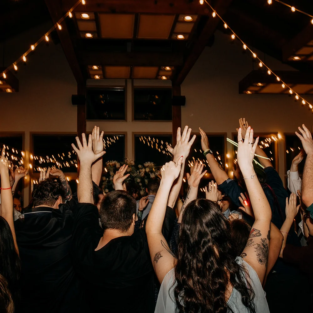 A packed wedding dance floor with every hand in the air at Whonnock Lake hall in Maple Ridge, British Columbia.